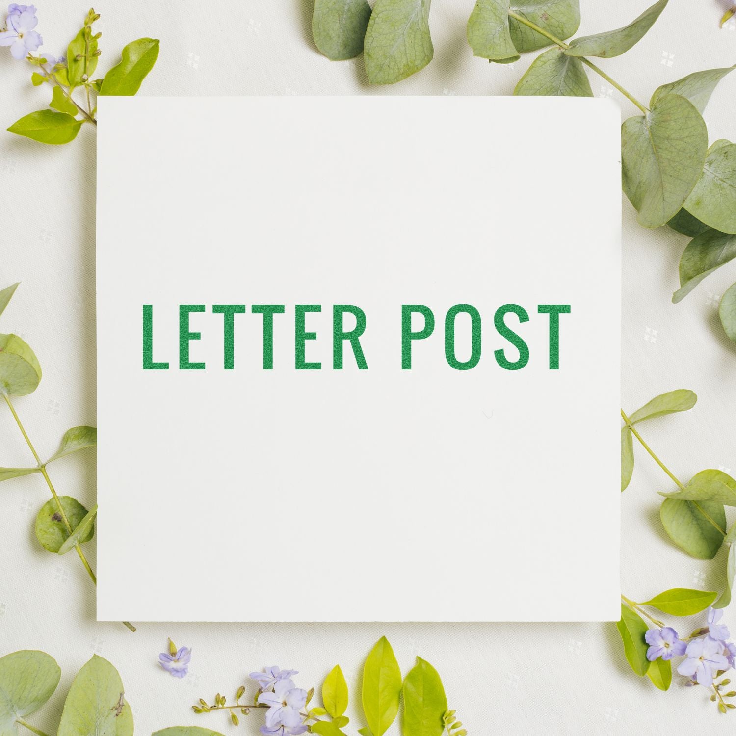 Letter Post rubber stamp on white paper surrounded by green leaves and small purple flowers.