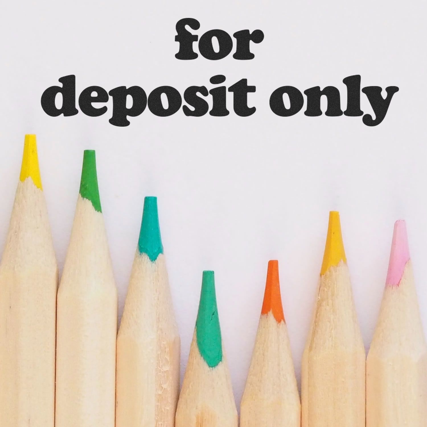 Colored pencils beneath a lowercase for deposit only rubber stamp imprint on white paper.