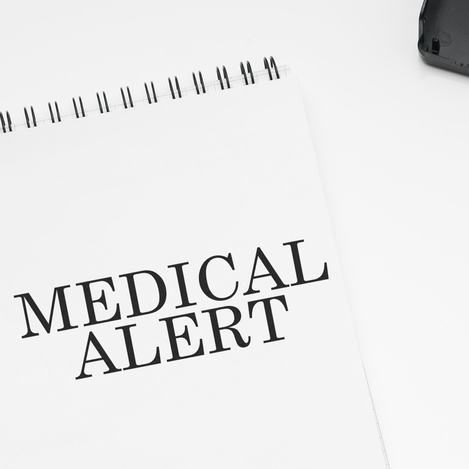 Medical Alert rubber stamp impression on a white spiral notebook with a black ink pad in the background.