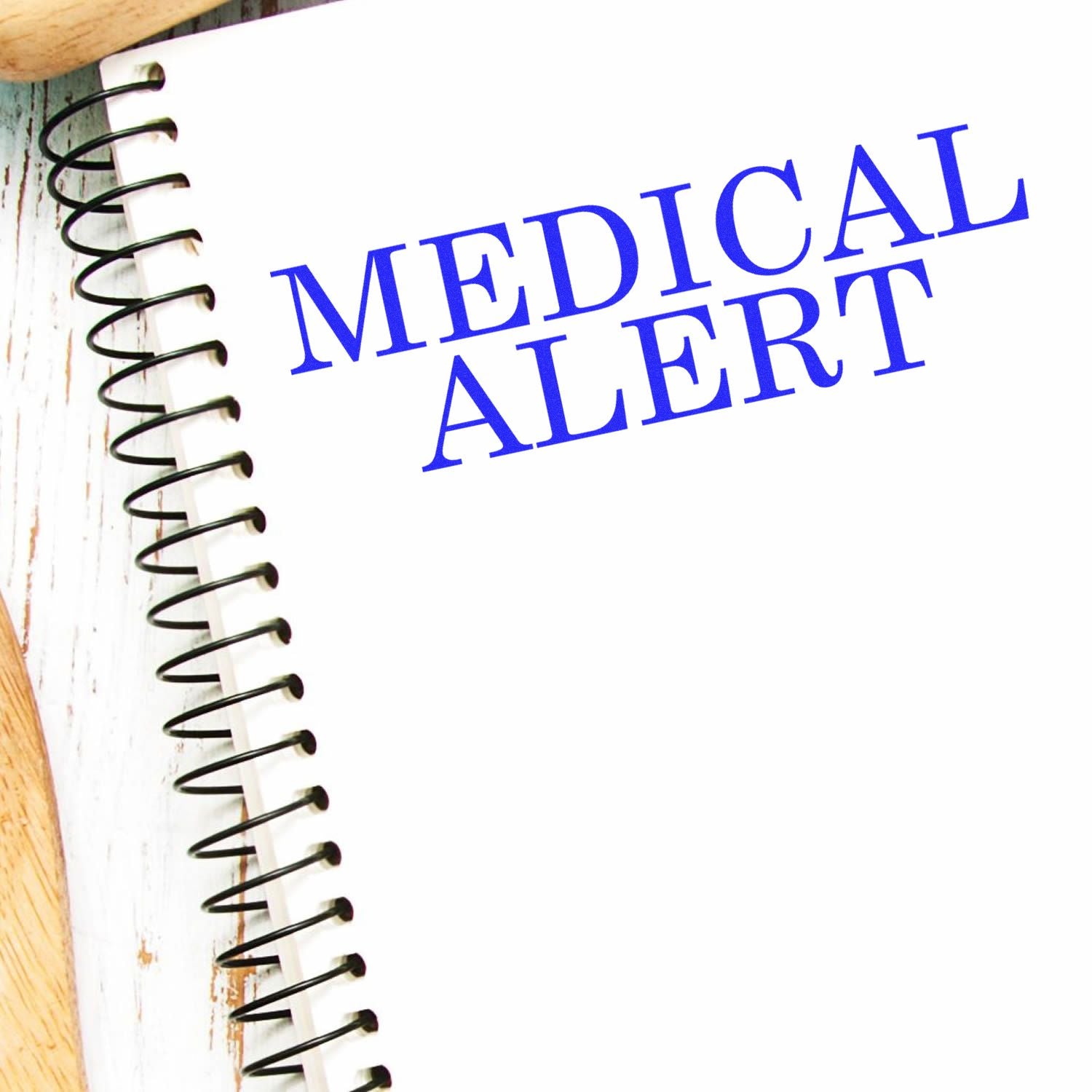 Medical Alert Rubber Stamp imprint in blue ink on a white spiral notebook, placed on a wooden surface.