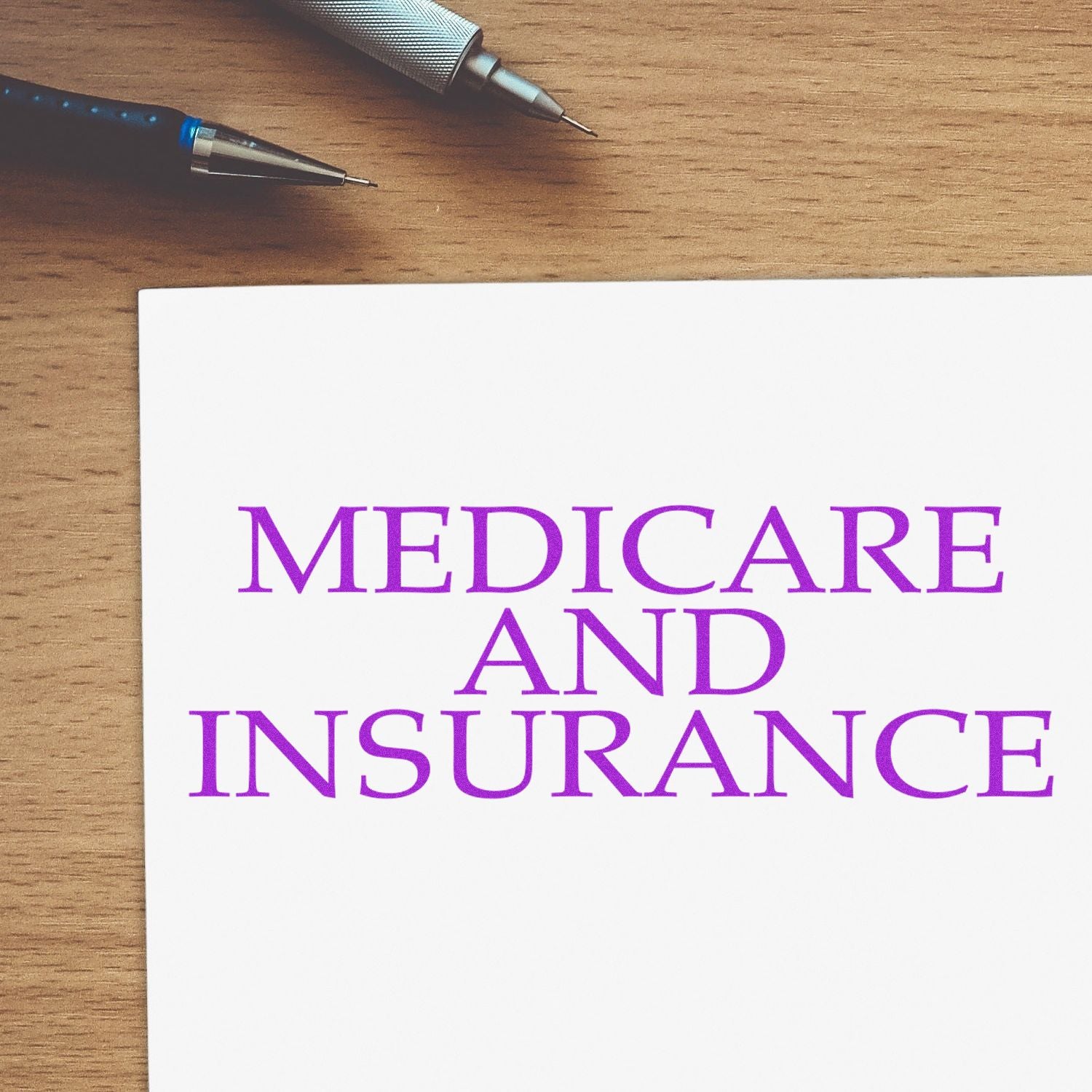 Medicare And Insurance Rubber Stamp in purple ink on white paper, with a pen and pencil on a wooden desk.