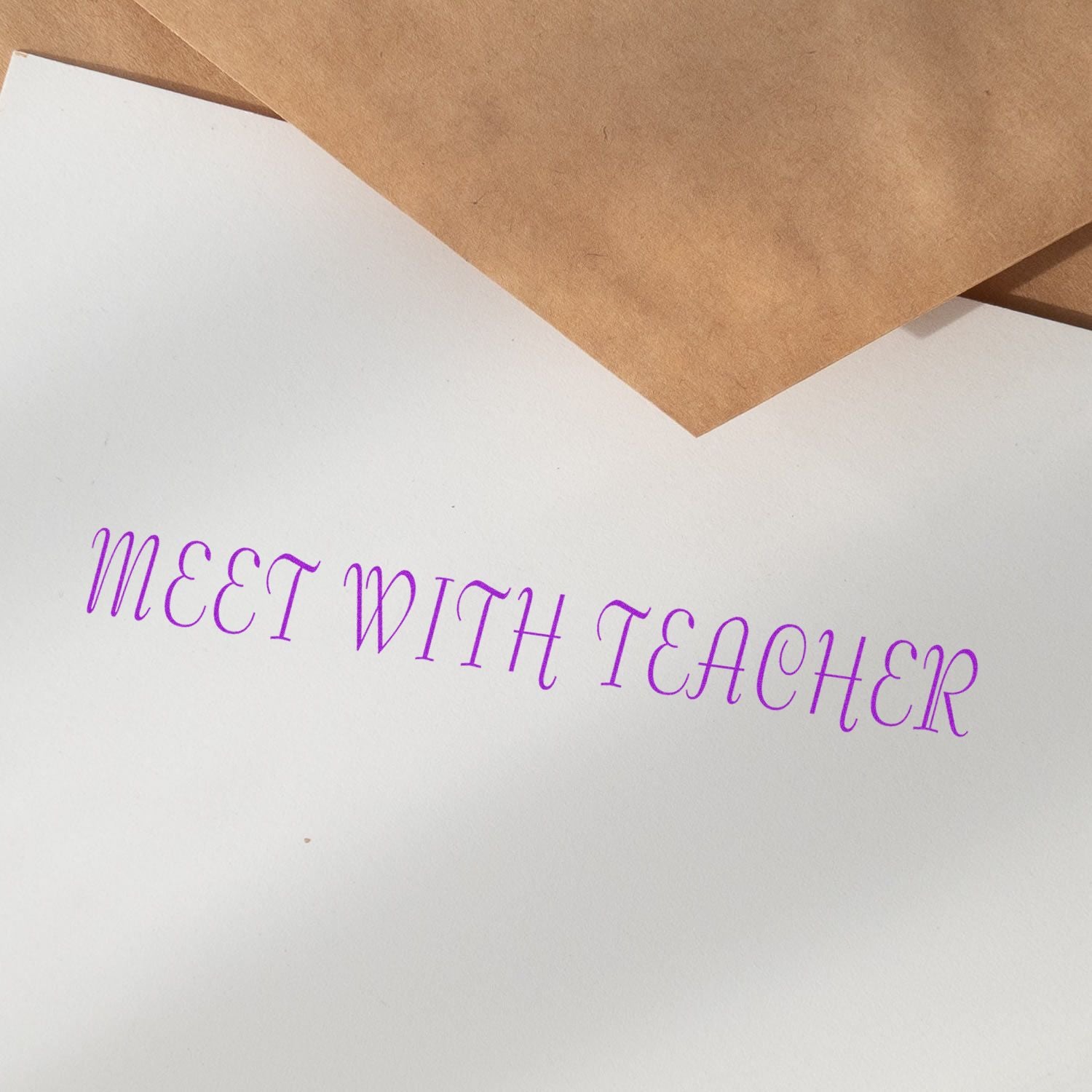 Meet With Teacher rubber stamp impression in purple ink on white paper, with brown envelopes in the background.