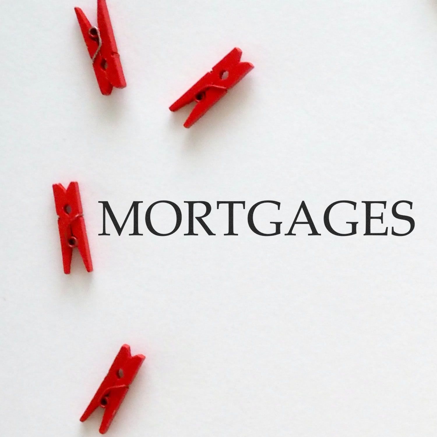 Red rubber stamp with the word 'Mortgages' stamped on white paper, surrounded by four small red clothespins.