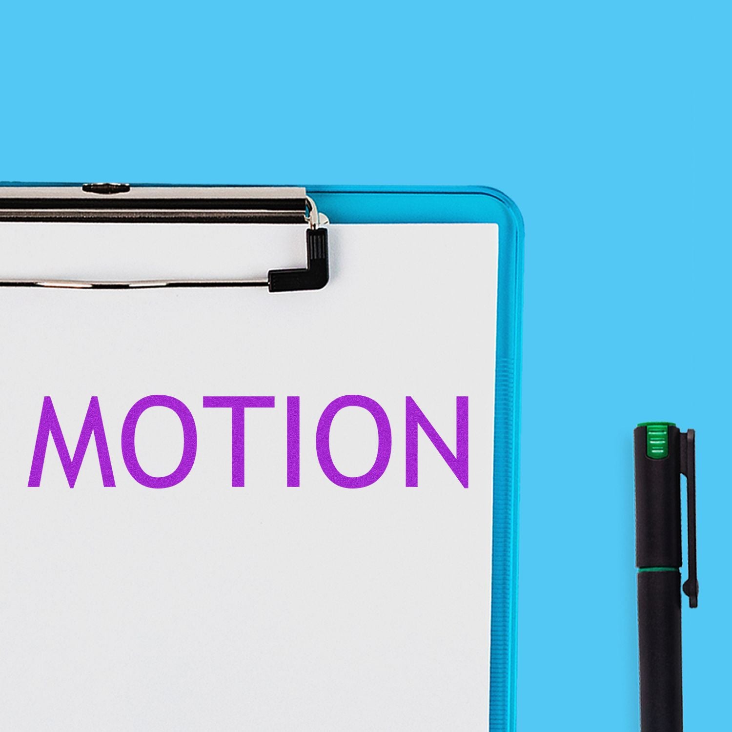 Large Motion Rubber Stamp imprinting the word MOTION in purple on a white paper clipped to a blue clipboard, with a black pen nearby.