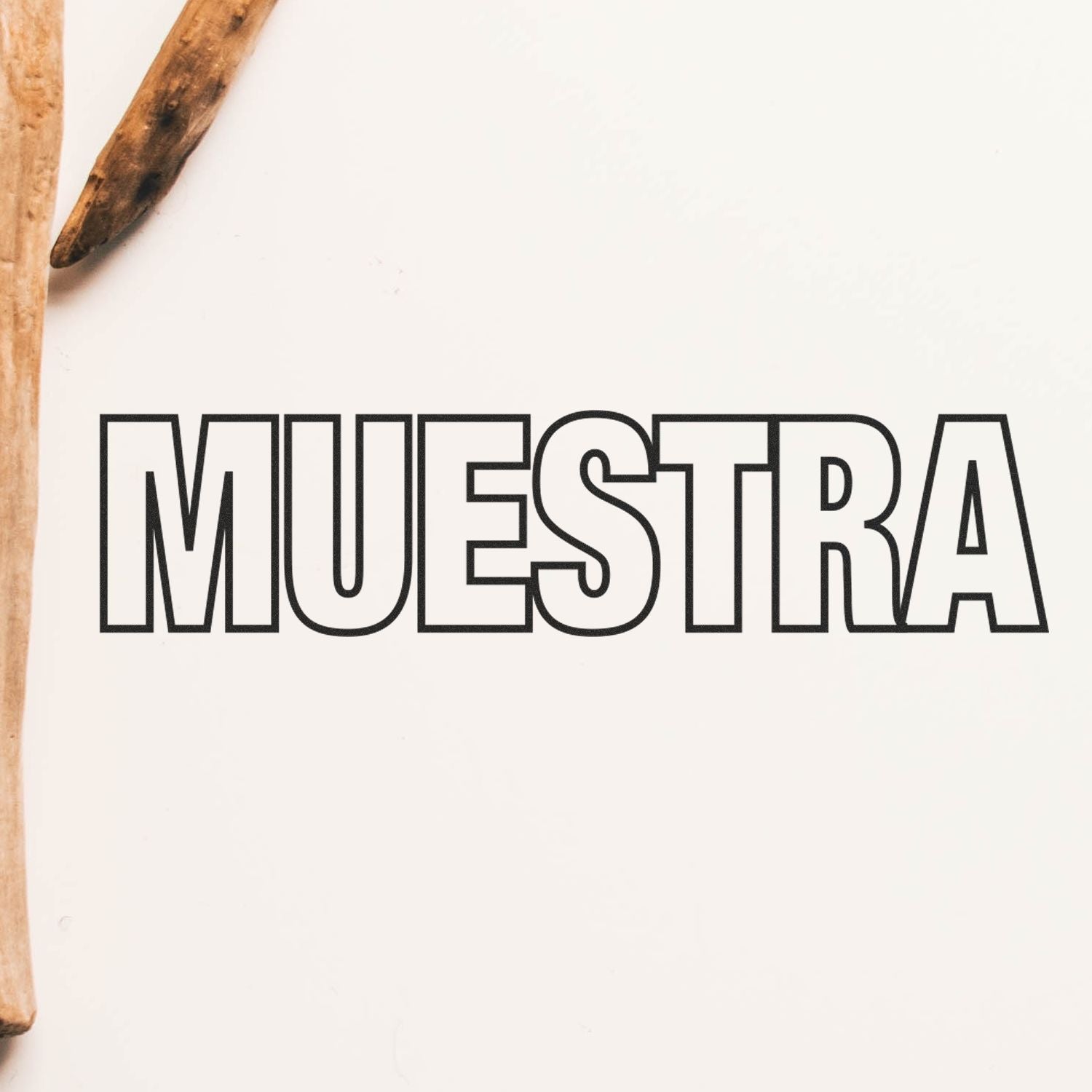 Muestra Rubber Stamp impression on a white surface with wooden sticks partially visible on the left side.