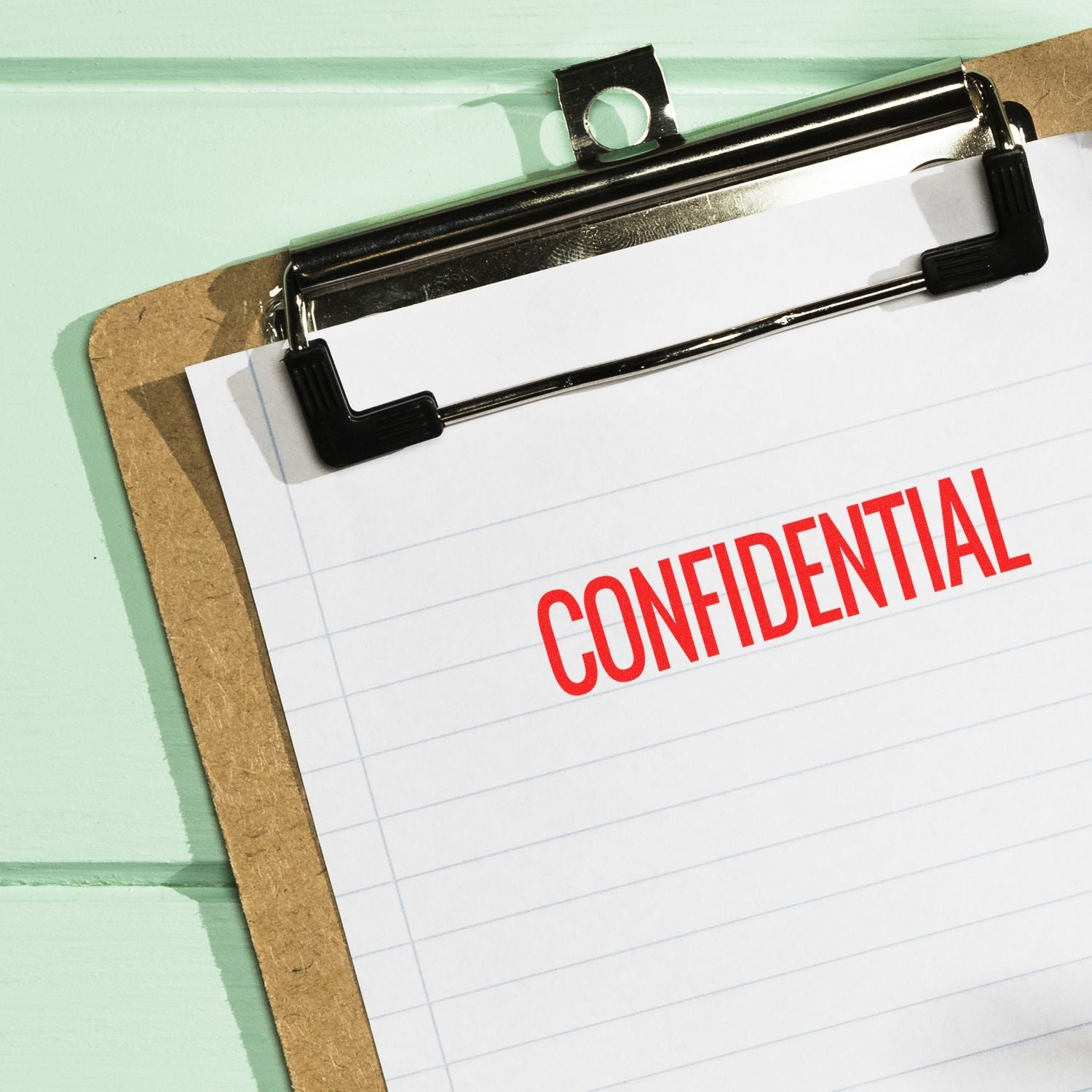 A clipboard with a sheet of paper stamped CONFIDENTIAL in red using the Self Inking Narrow Confidential Stamp.