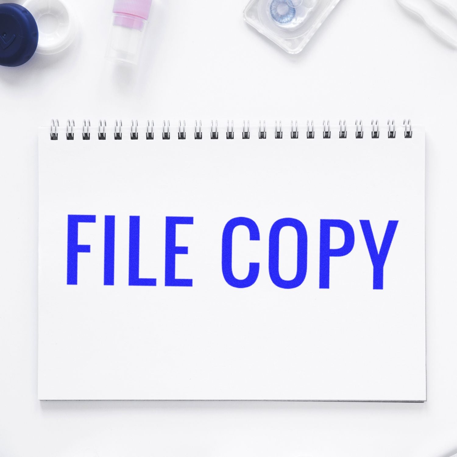 Large Narrow Font File Copy Rubber Stamp used on a white spiral notebook, surrounded by office supplies on a white background.