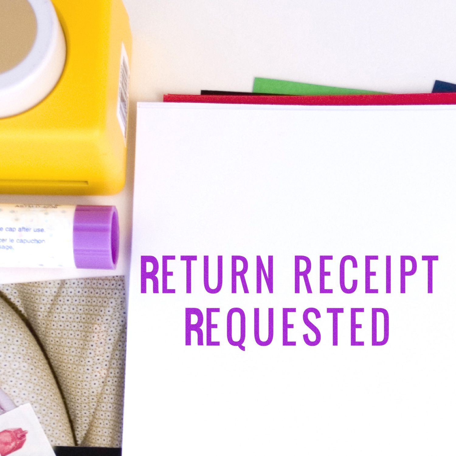 Large Narrow Font Return Receipt Requested Self Inking Stamp image in purple ink on white paper, surrounded by office supplies.