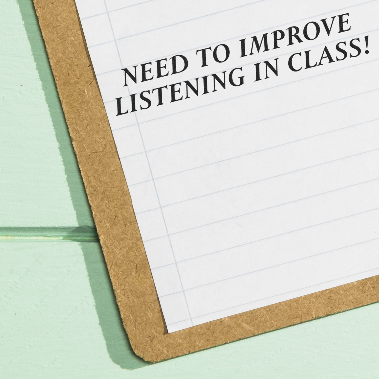 Need To Improve Listening In Class rubber stamp impression on lined paper attached to a clipboard on a light green surface.