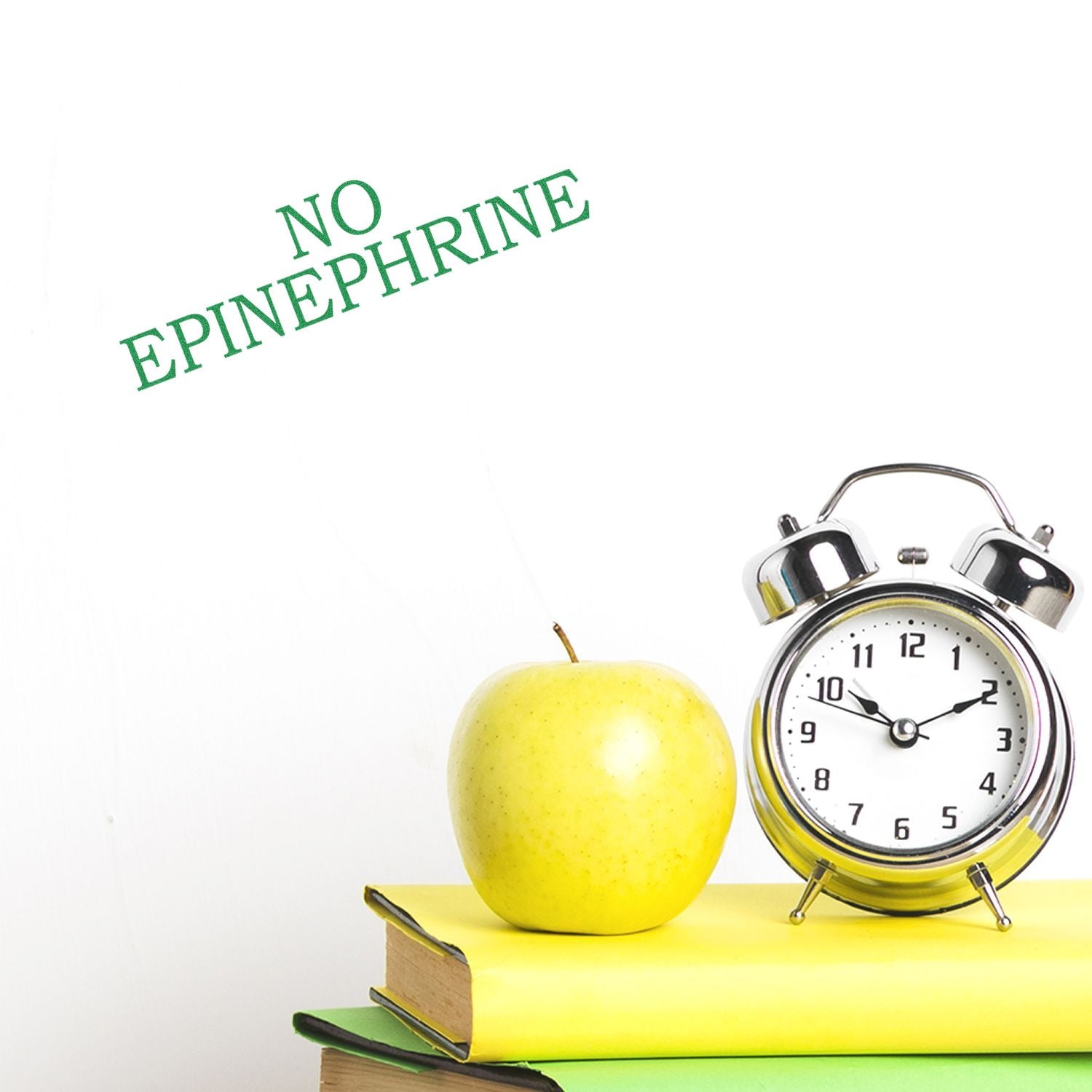 Large No Epinephrine Rubber Stamp in use, stamping NO EPINEPHRINE in green ink. An apple, clock, and books are in the background.