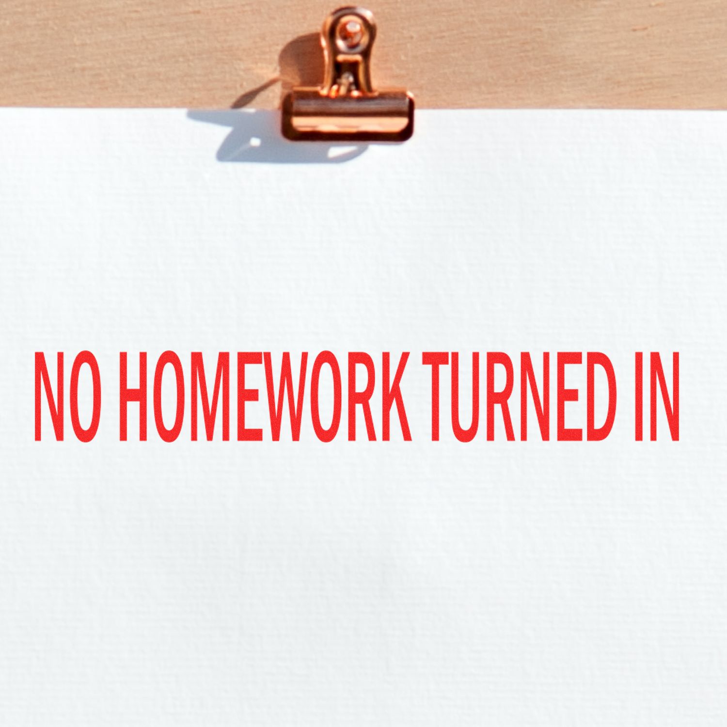 No Homework Turned In rubber stamp impression in red ink on white paper clipped to a wooden board.