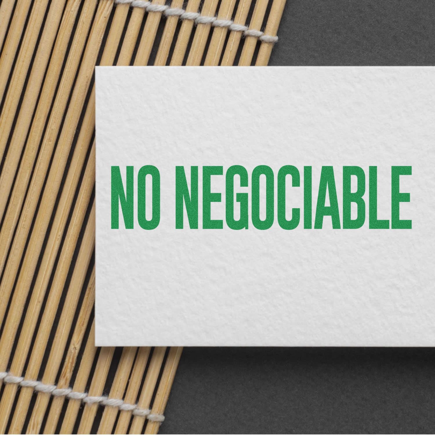 No Negociable rubber stamp imprint in green ink on a white card, placed on a bamboo mat background.