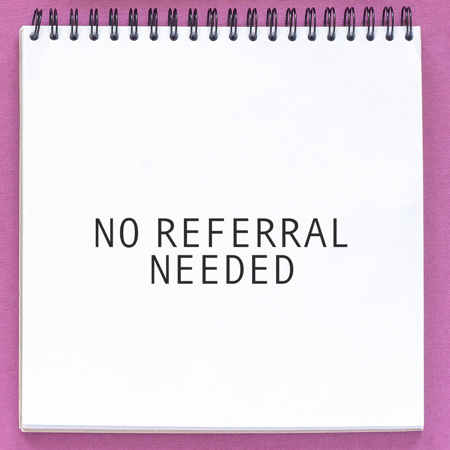 A white notepad with NO REFERRAL NEEDED stamped on it using the Self Inking No Referral Needed Stamp, against a pink background.