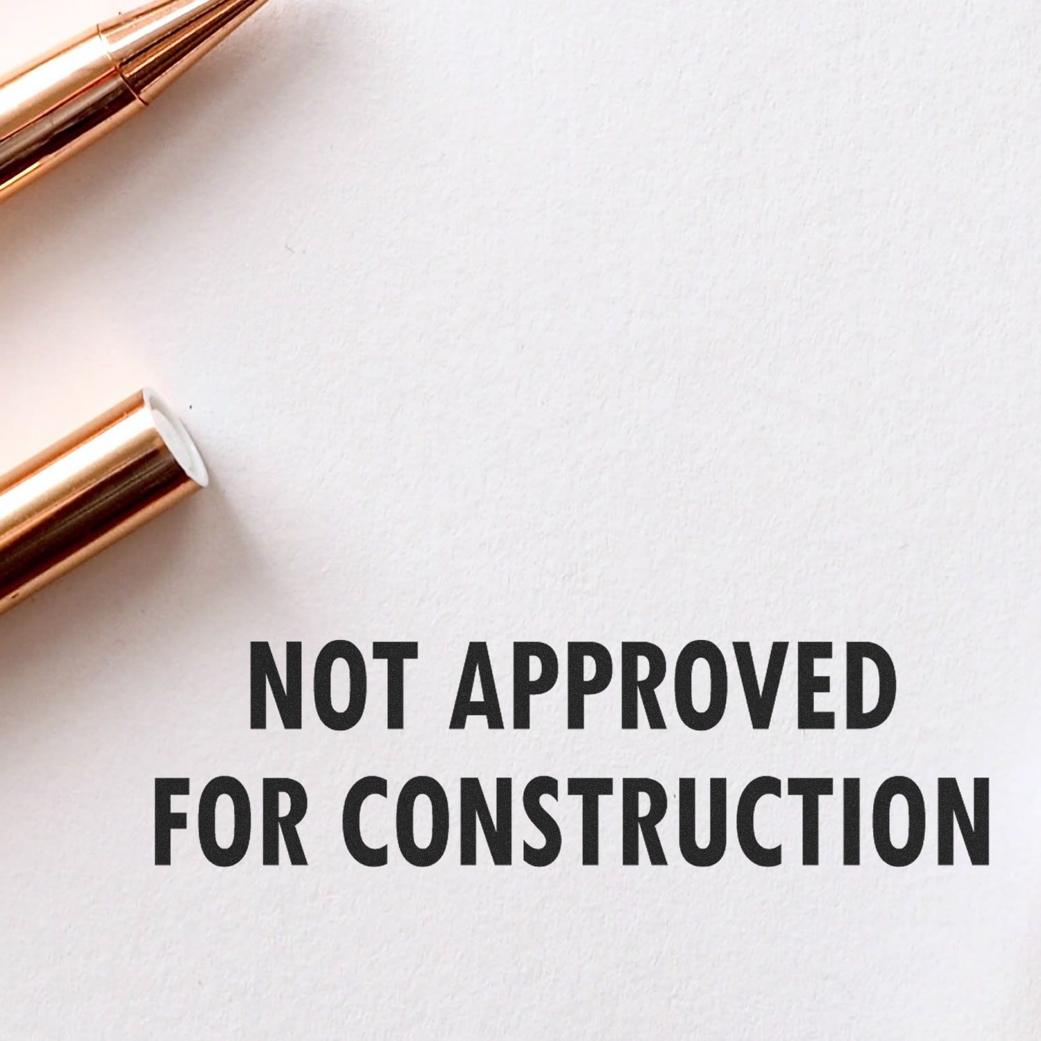 Not Approved For Construction rubber stamp impression on white paper with a pen nearby.