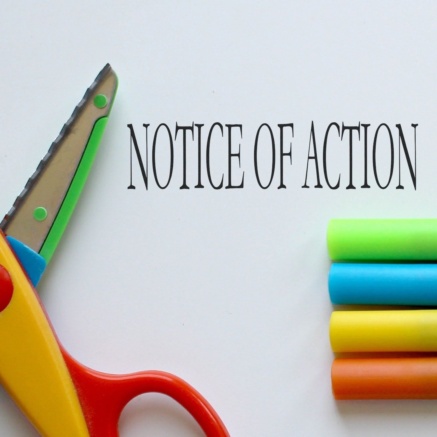 Notice Of Action rubber stamp with colorful scissors and markers on a white background.