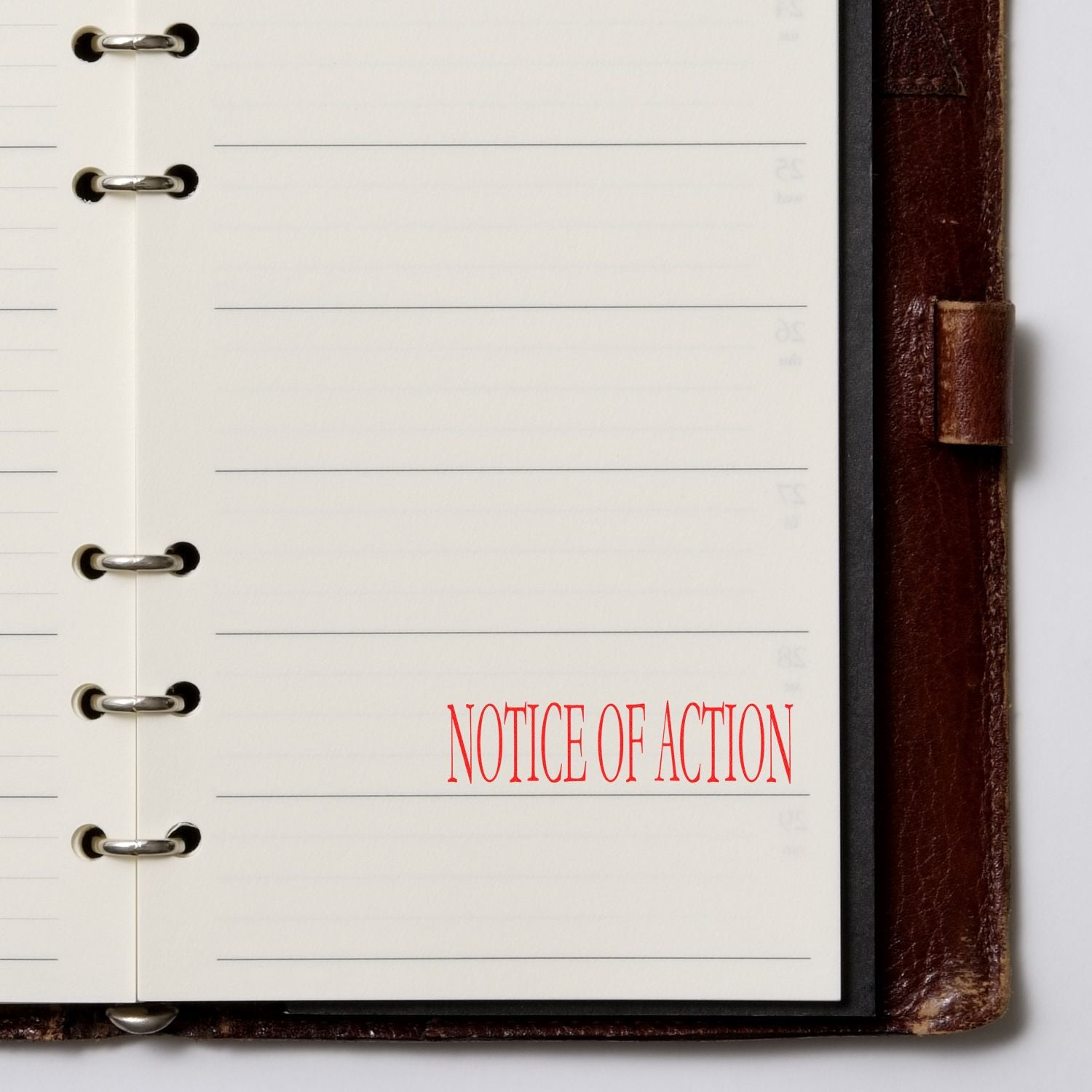 Notice Of Action Rubber Stamp in red ink on a lined notebook page within a brown leather binder.