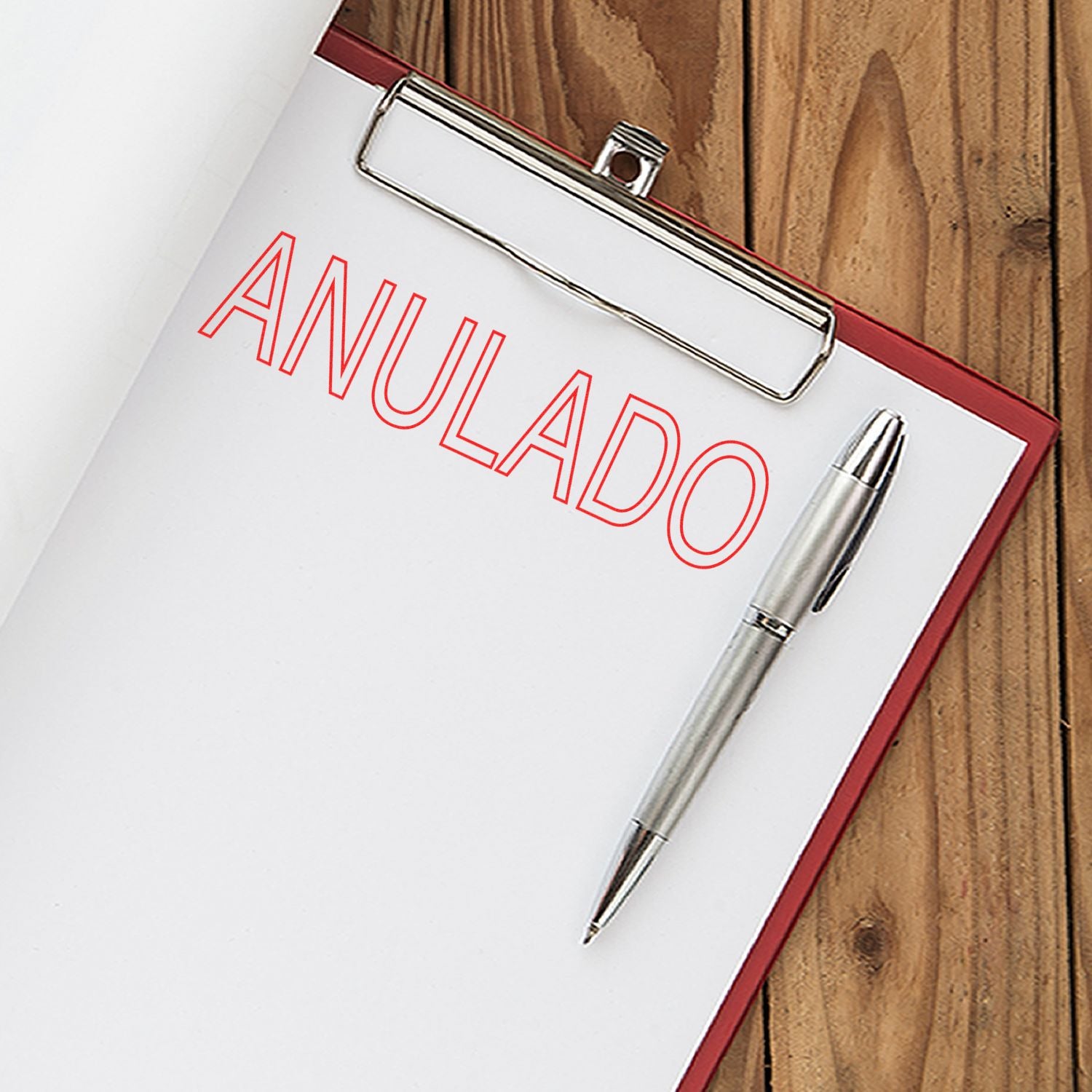 Clipboard with a sheet stamped ANULADO in red using the Large Outline Anulado Rubber Stamp, next to a silver pen on a wooden surface.