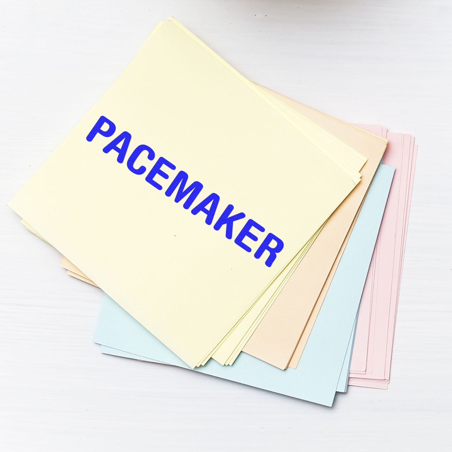 Large Pacemaker Rubber Stamp imprint on a stack of pastel-colored papers, with the word PACEMAKER clearly visible in bold blue letters.