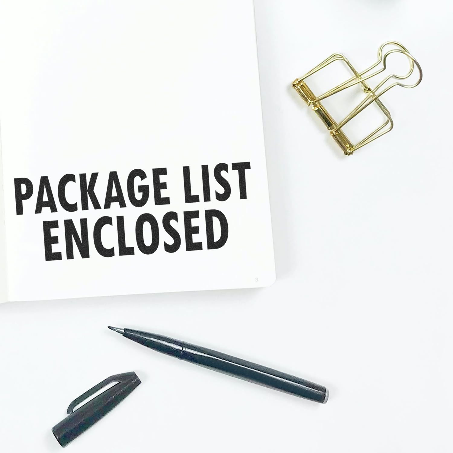 Self Inking Package List Enclosed Shipping Stamp used on a white paper, with a pen and a gold binder clip nearby.