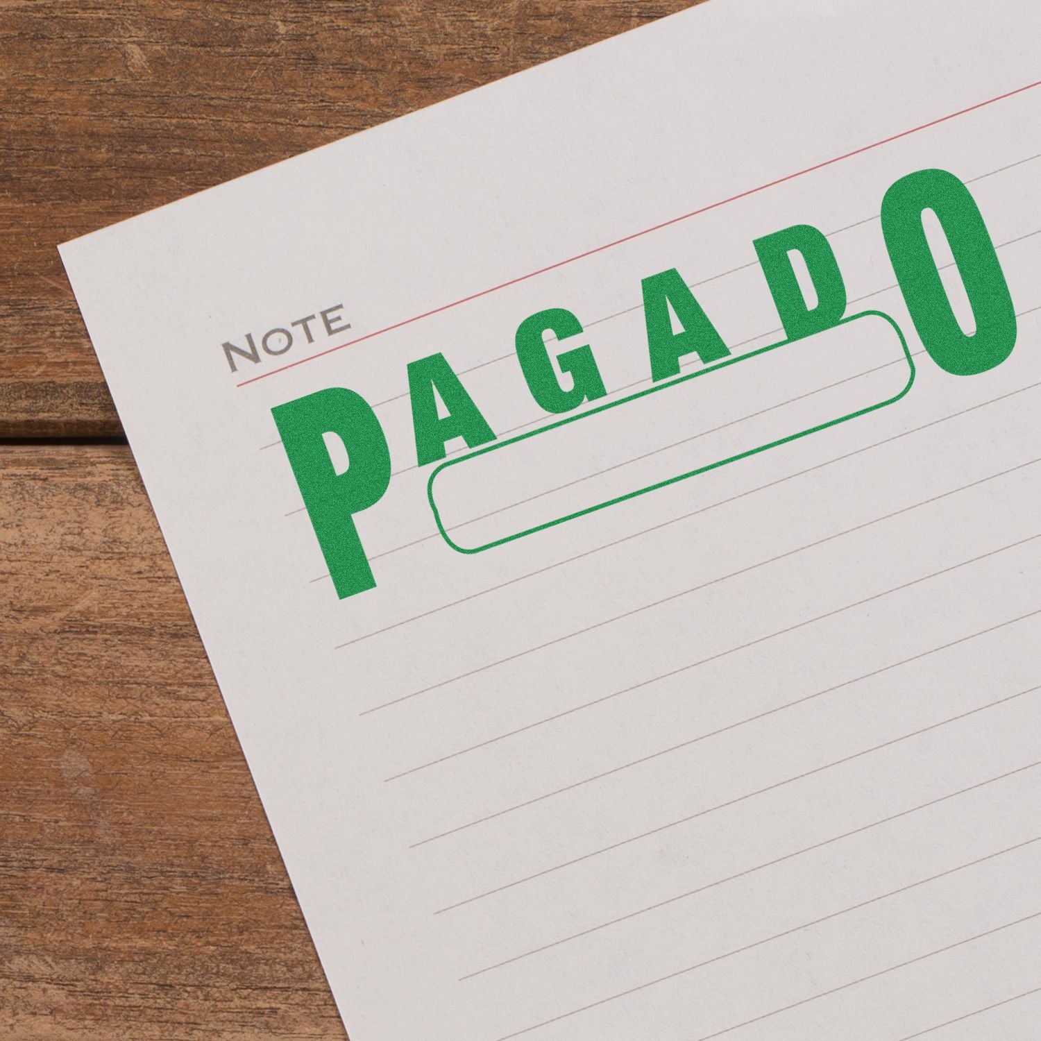 Large Pre-Inked Pagado with Box Stamp in green ink on a lined paper with Note heading, placed on a wooden surface.