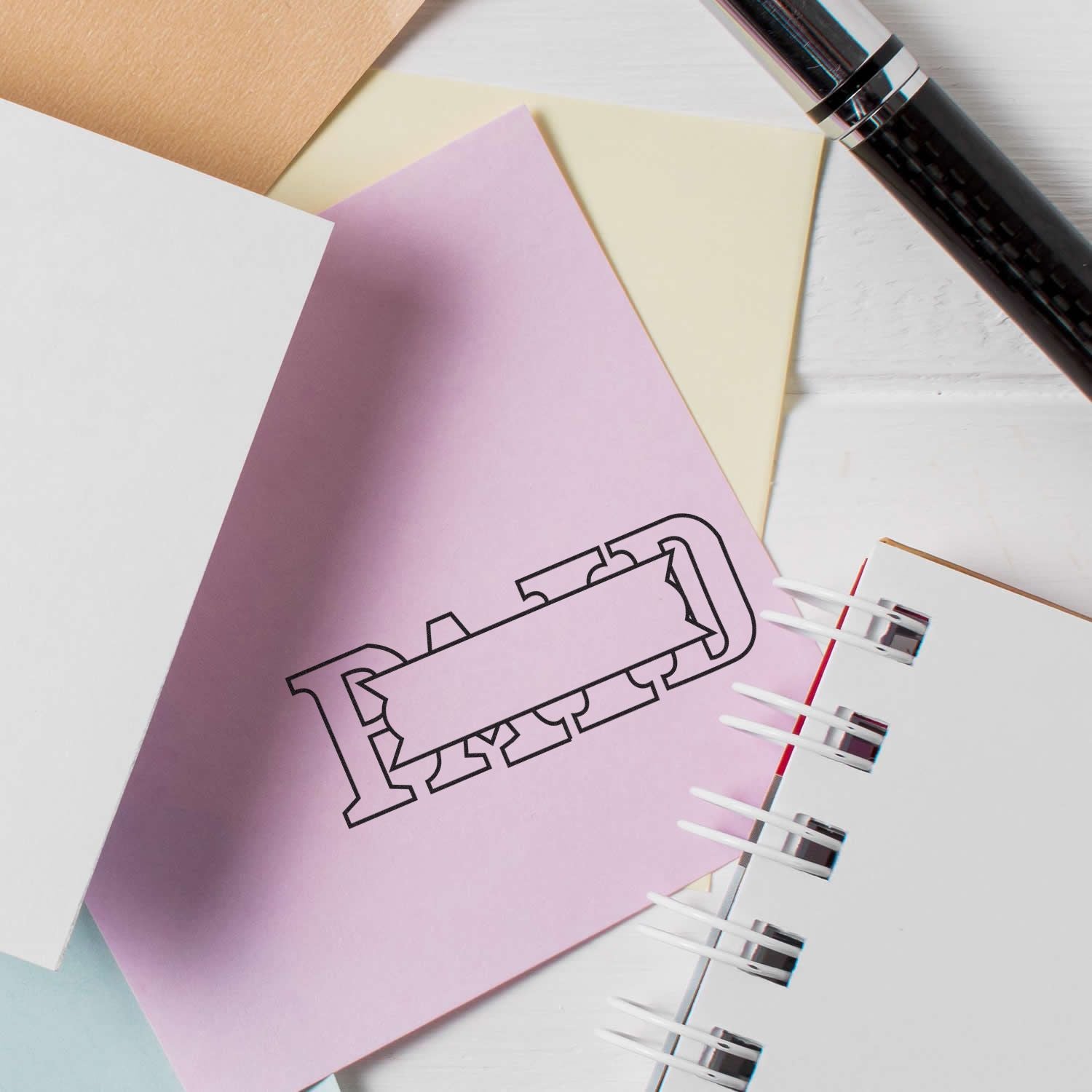 Large Self Inking Paid with Box Stamp used on a pink paper, surrounded by other papers and a pen.