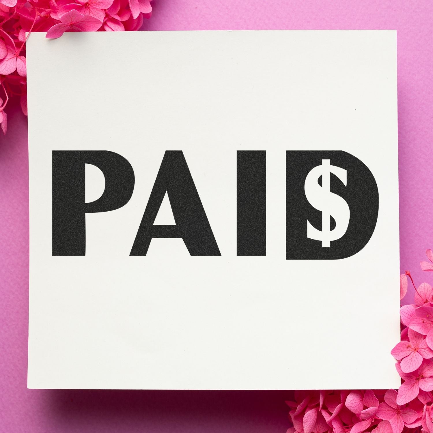 Self Inking Paid with Dollar Sign Stamp on white paper, surrounded by pink flowers on a pink background.