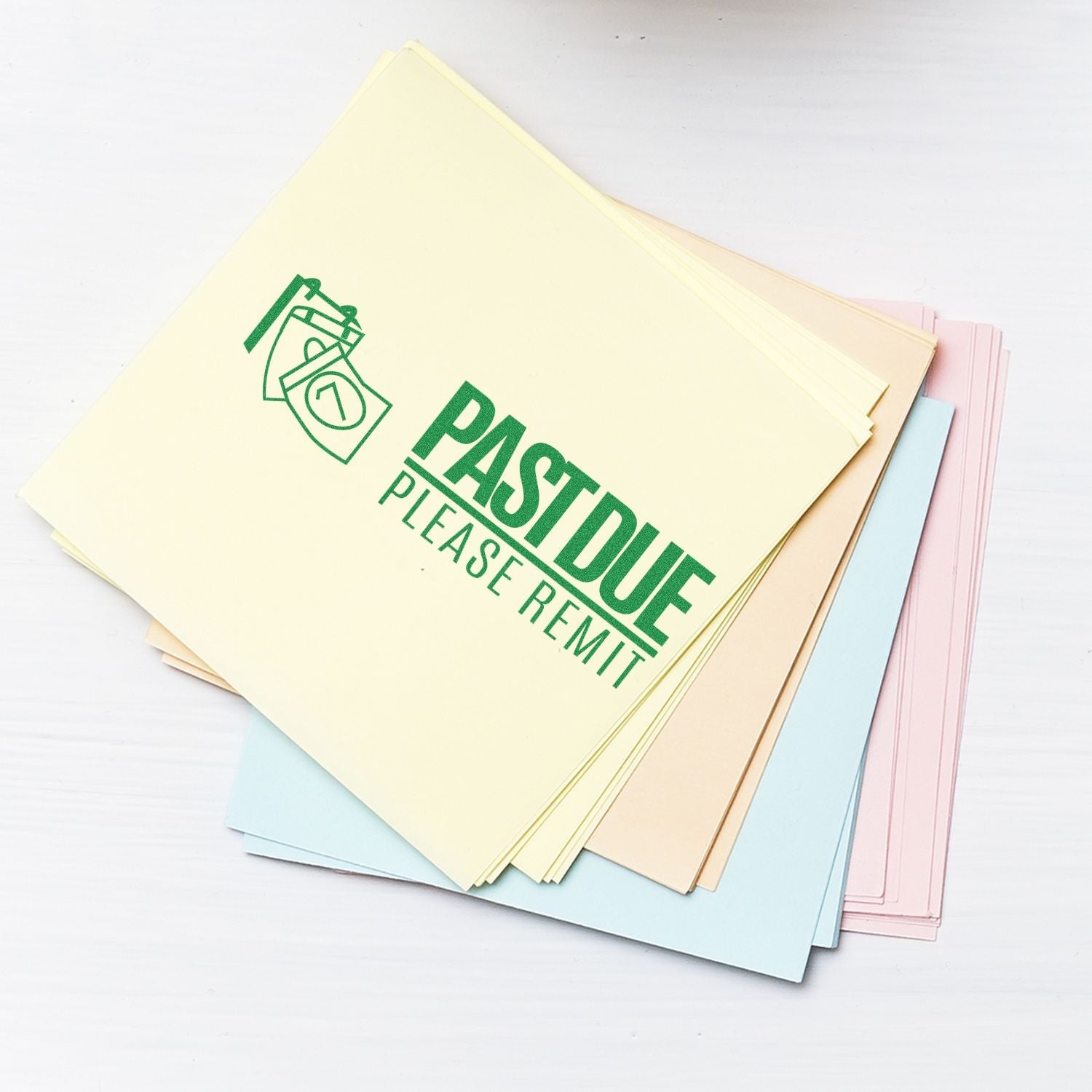 Stack of pastel papers stamped with Self Inking Past Due Please Remit with Calendar Stamp in green ink on a white surface.