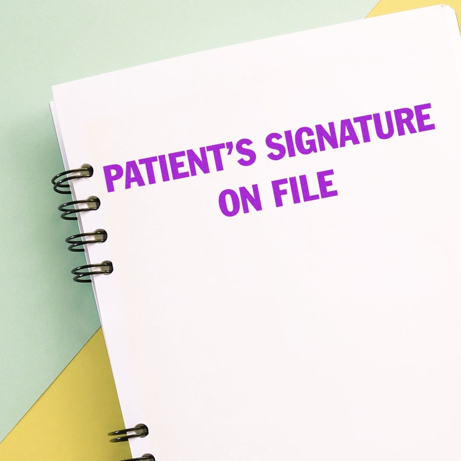 Self Inking Patient's Signature on File Stamp used on a spiral-bound notebook with PATIENT'S SIGNATURE ON FILE in bold purple text.