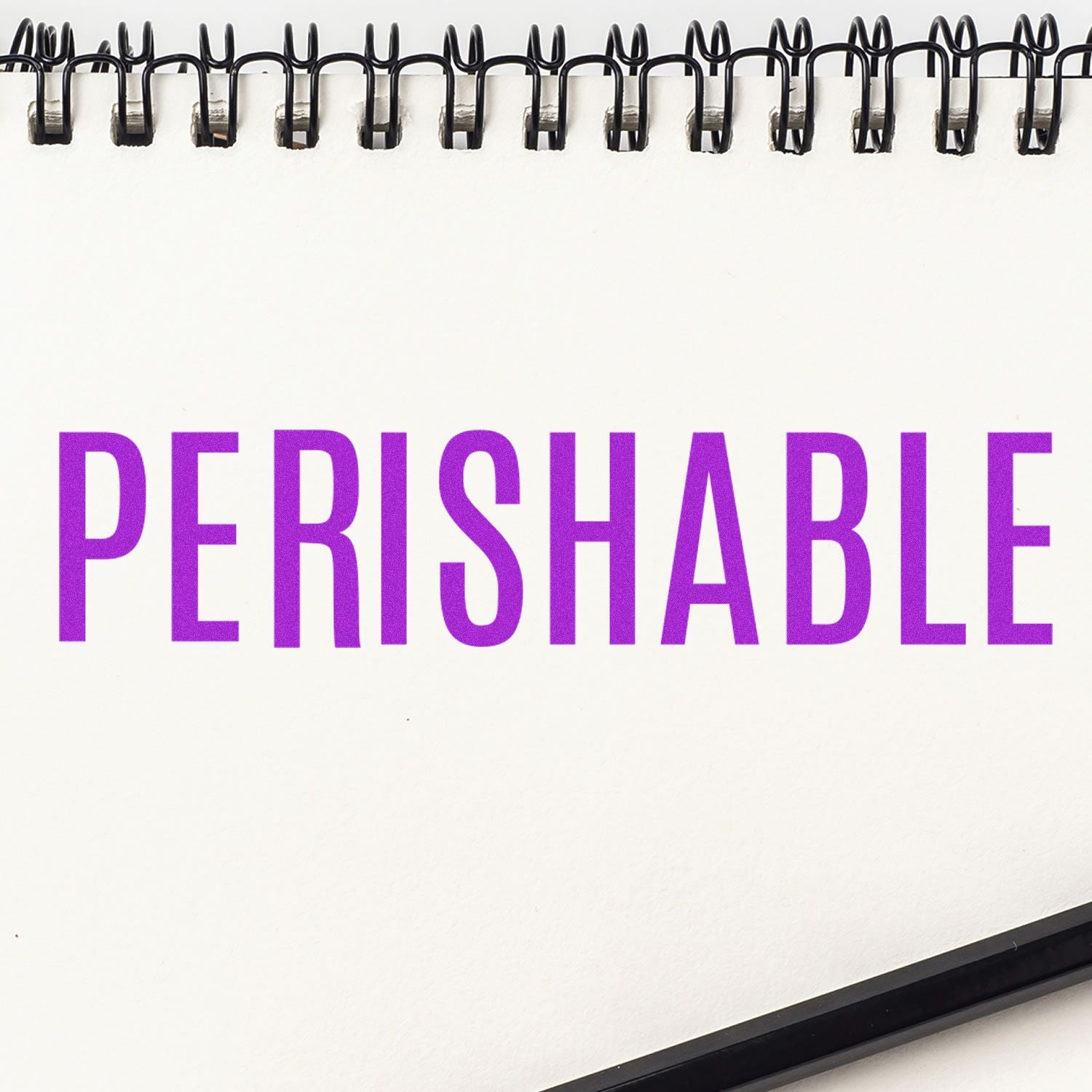 Self Inking Perishable Stamp in use, displaying the word PERISHABLE in bold purple letters on a white notepad with a black spiral binding.