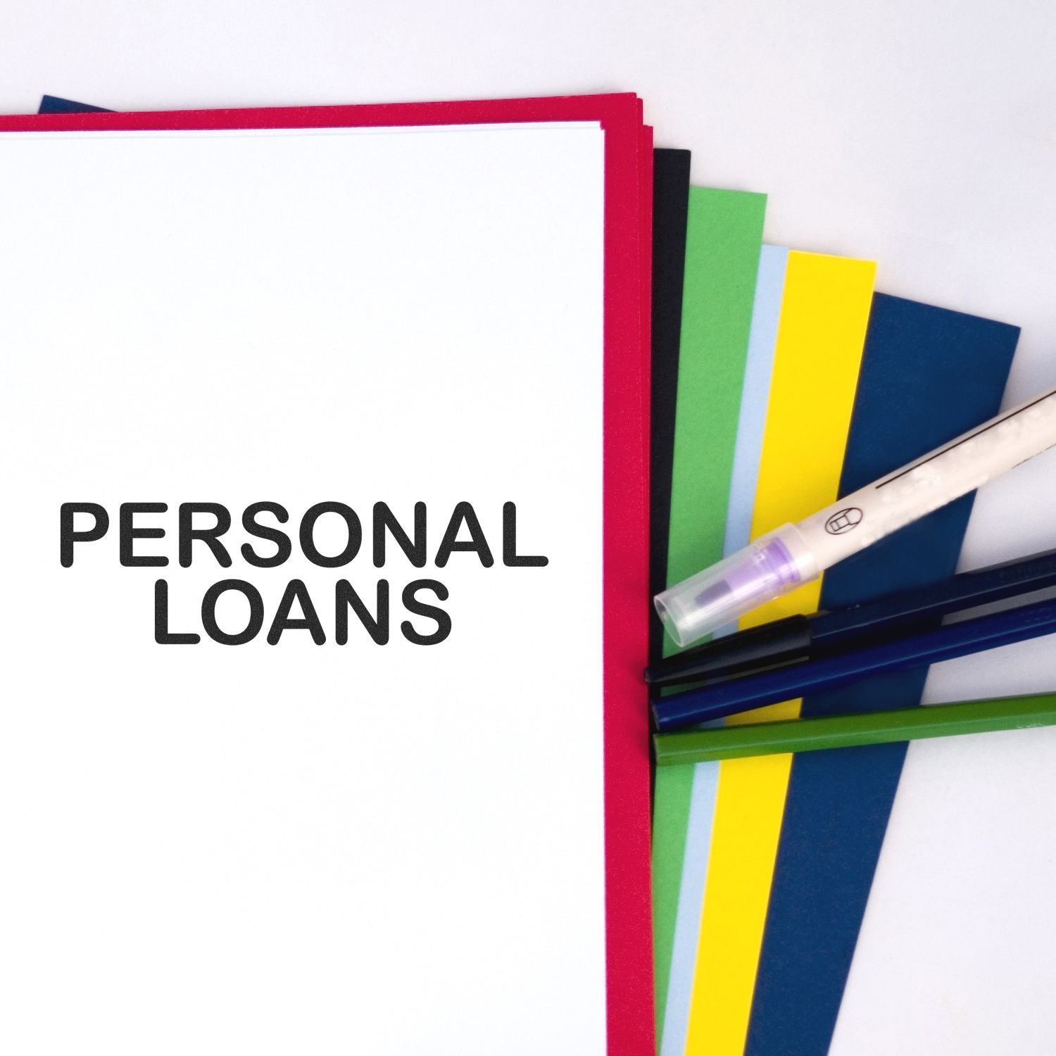 A stack of colorful papers with PERSONAL LOANS stamped on the top sheet using the Large Personal Loans Rubber Stamp, alongside pens.