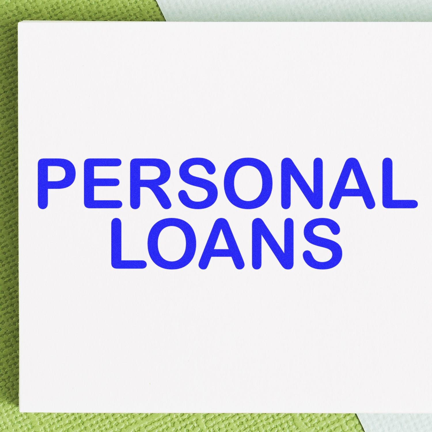 Large Personal Loans Rubber Stamp imprint in bold blue letters on white paper, placed on a textured green surface.