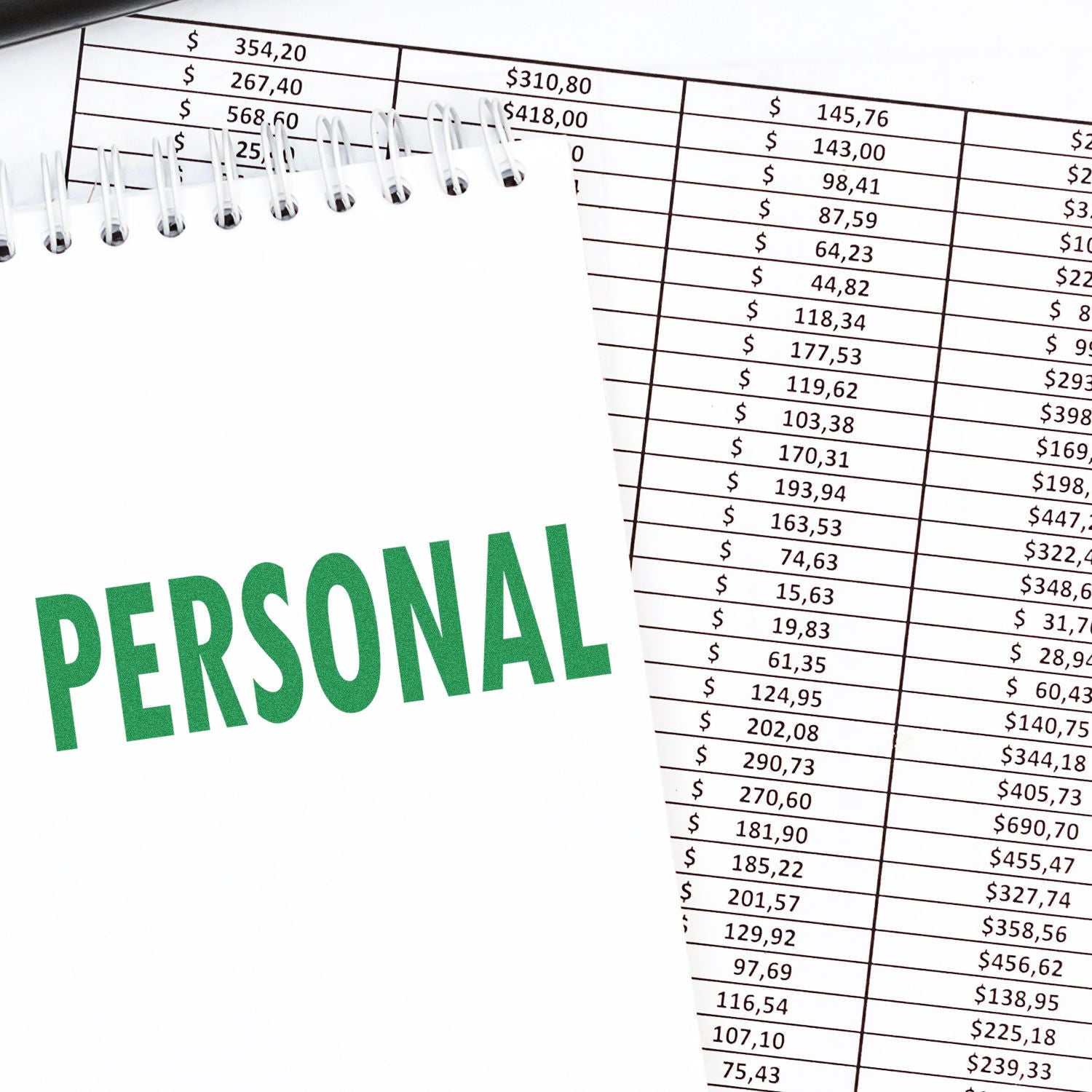 A Large Personal Rubber Stamp marks PERSONAL in green on a white notepad, placed over a financial spreadsheet.