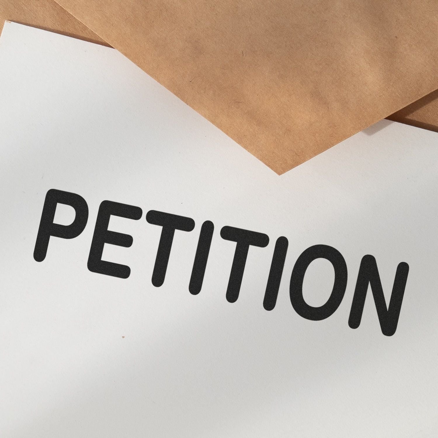 Paper stamped with the word PETITION using the Self Inking Petitioner Stamp, with brown envelopes in the background.