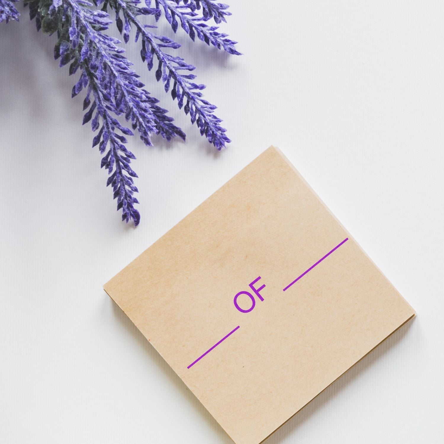 Self Inking Pkg Of Stamp on a beige card with purple text, placed on a white surface next to lavender flowers.