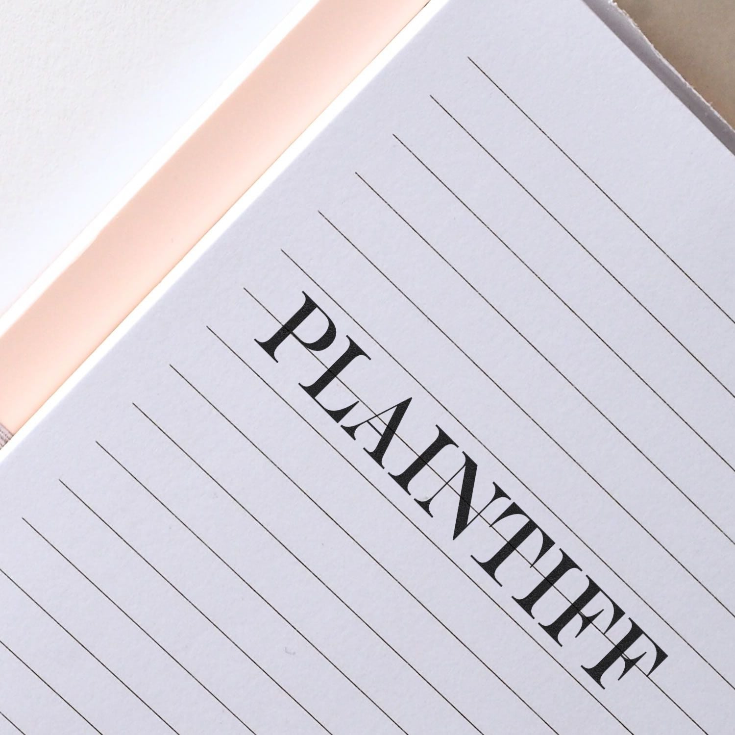 A notebook page stamped with the word PLAINTIFF in bold, black letters using a Plaintiff Rubber Stamp.