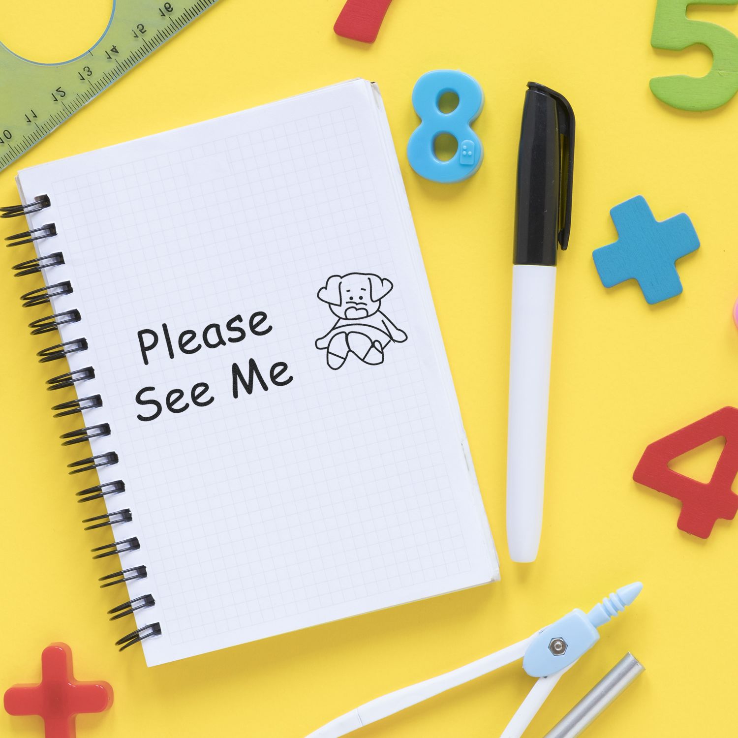 Please See Me rubber stamp on a notebook with a dog illustration, surrounded by colorful numbers, a pen, and stationery on a yellow background.