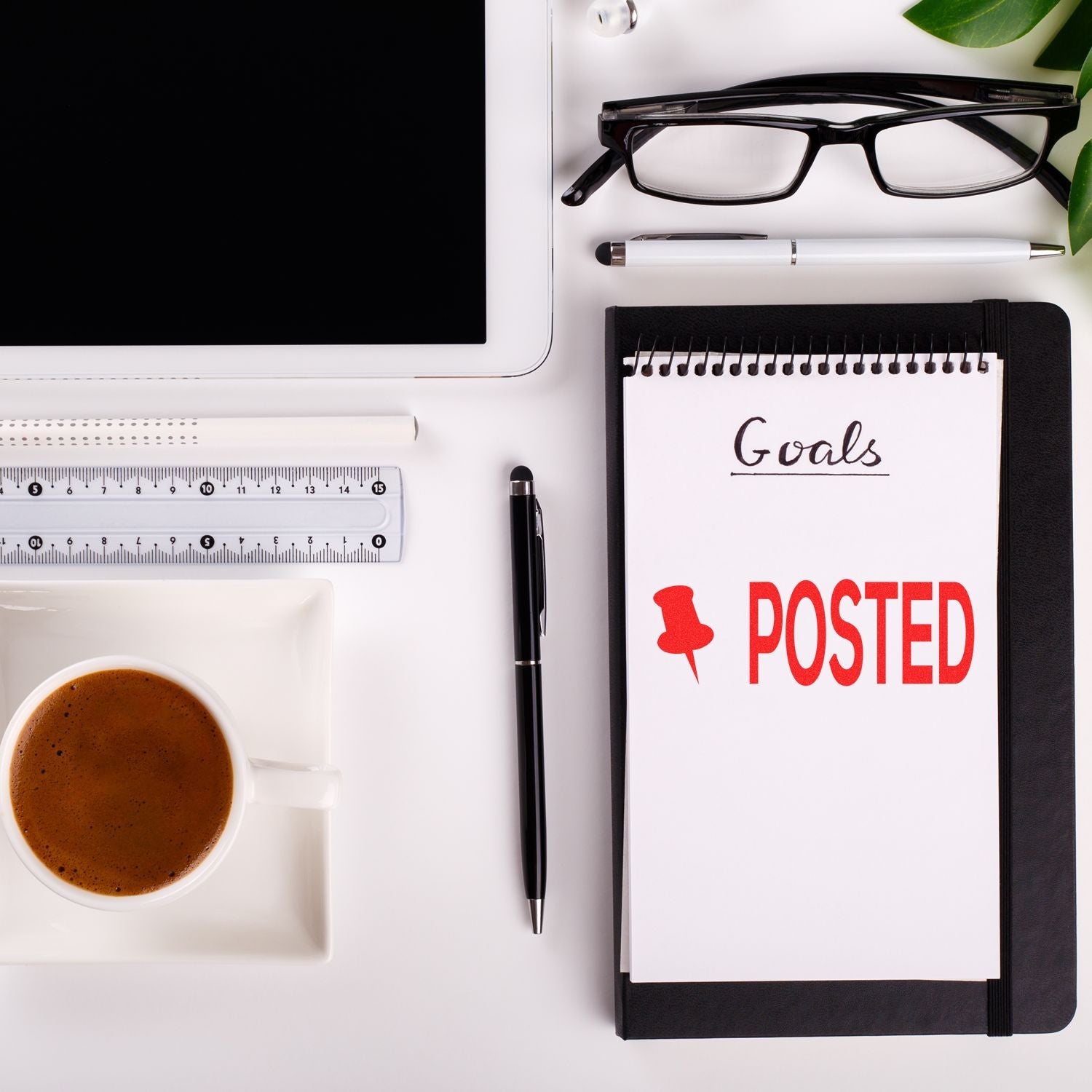 Self Inking Posted with Thumbtack Stamp marking POSTED on a notepad, surrounded by office supplies, a coffee cup, and a tablet.