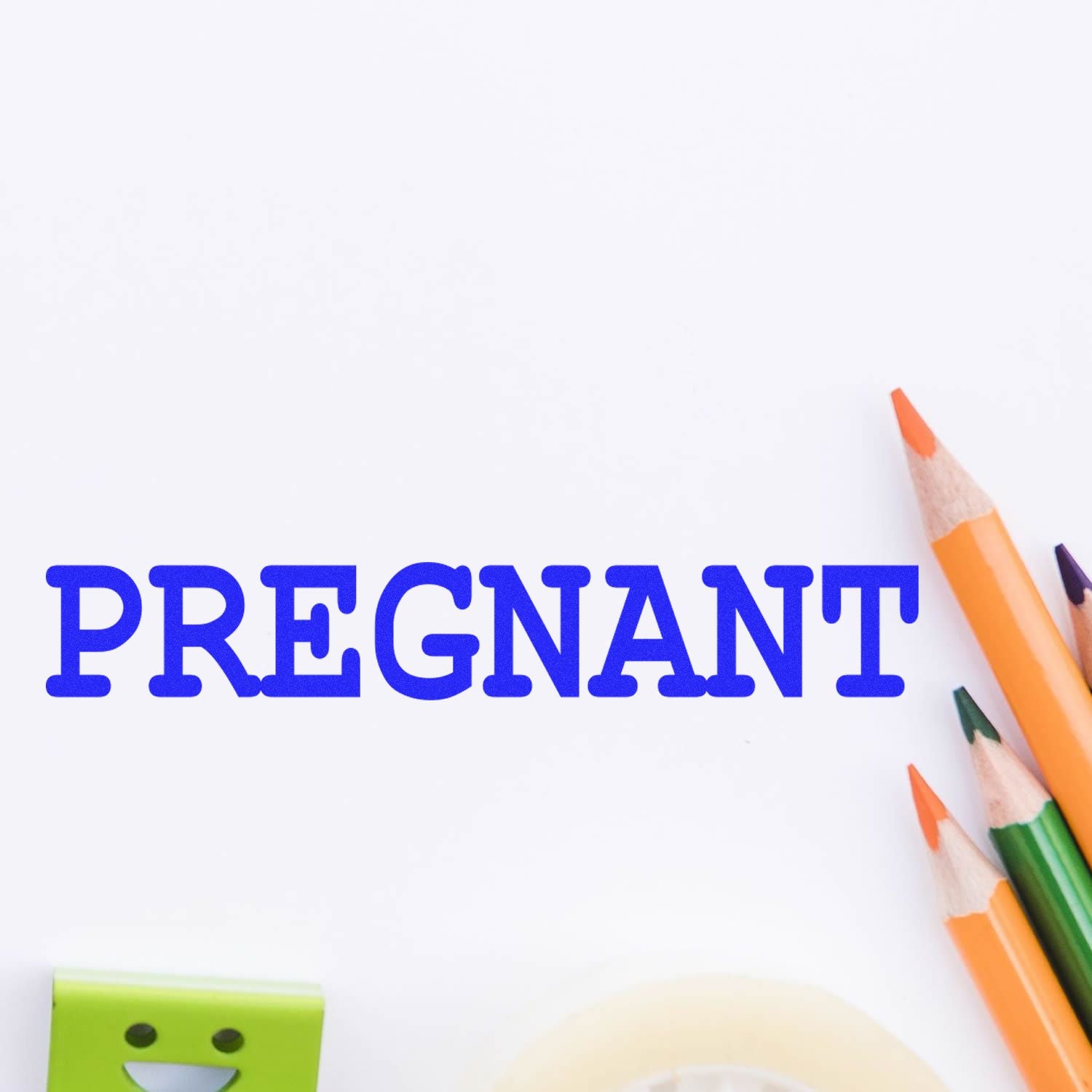 Large Pregnant Rubber Stamp in use, displaying the word 'PREGNANT' in blue ink on white paper, surrounded by colored pencils and stationery.