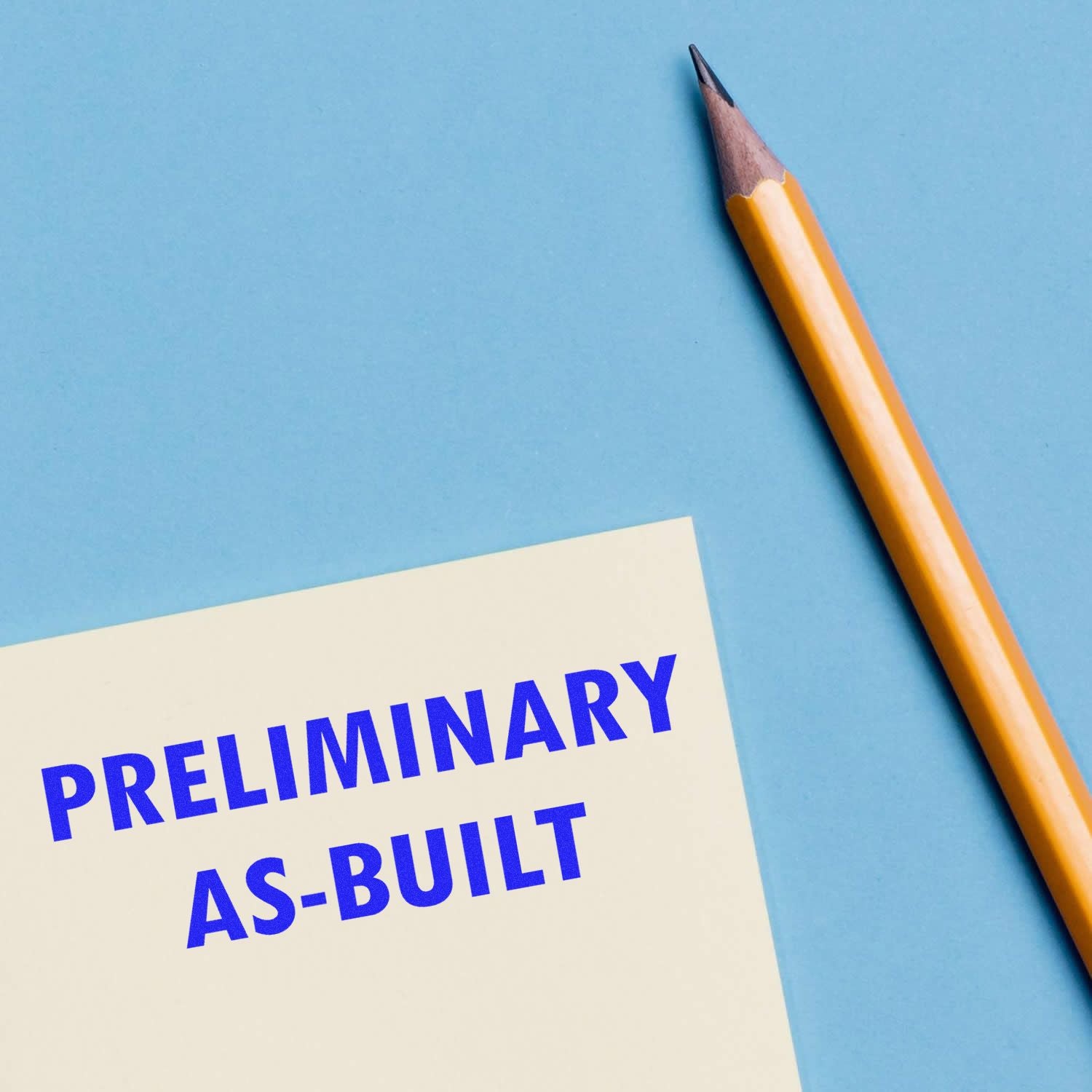 Large Self Inking Preliminary As-Built Stamp in use on a white paper next to a yellow pencil on a blue background.