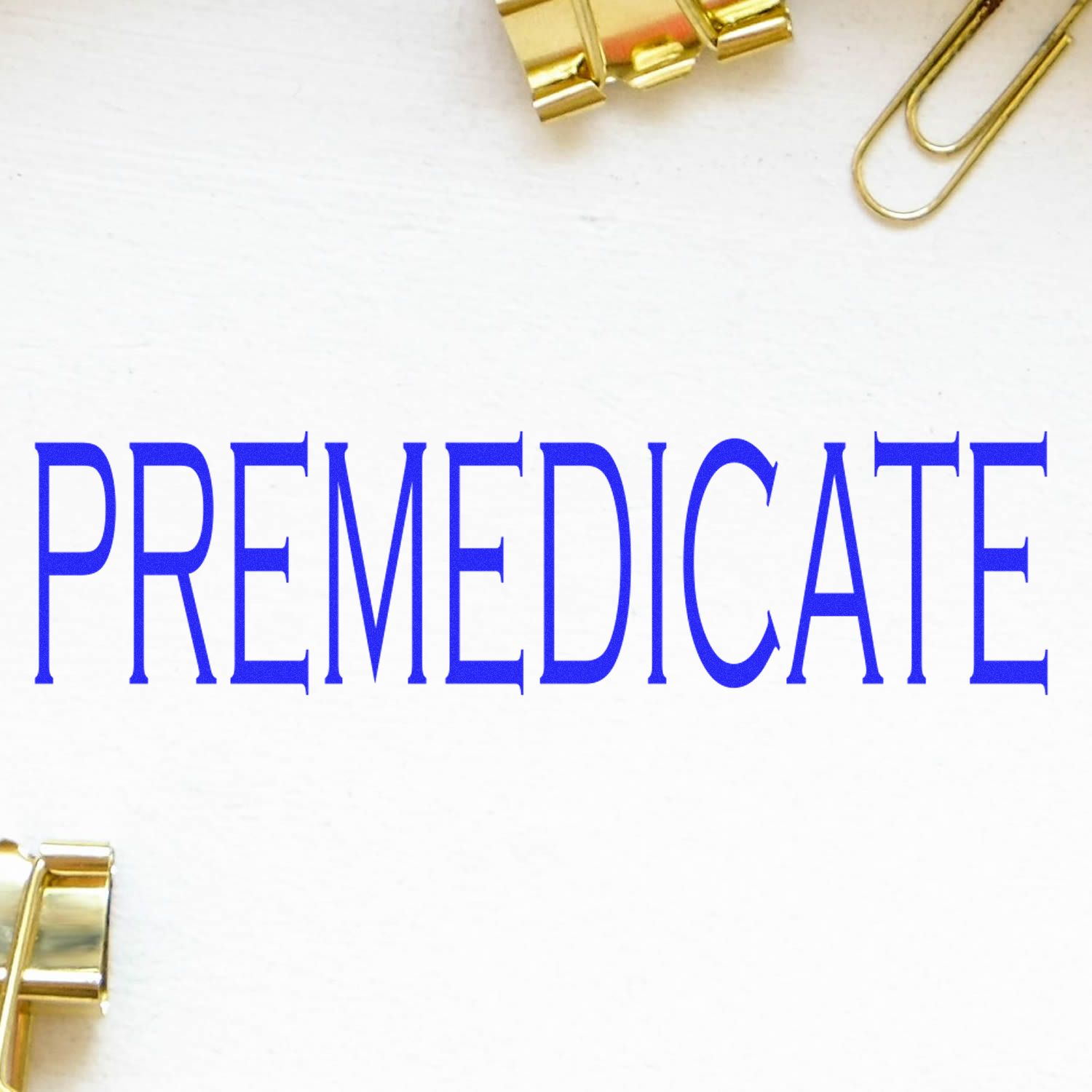 Blue 'PREMEDICATE' rubber stamp impression on white paper with gold paper clips in the background.