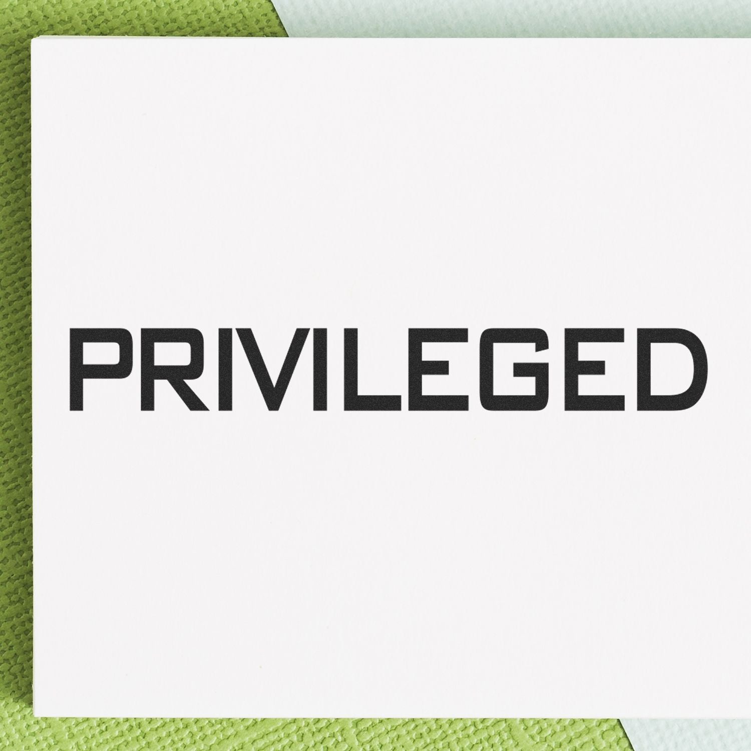 Close-up of a 'Privileged' rubber stamp on a white background with green textured surface underneath.