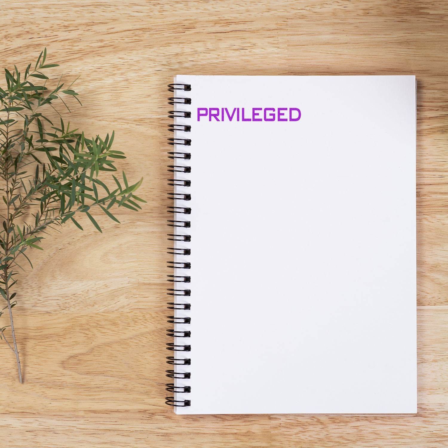 Notebook on wooden table stamped with 'Privileged' in purple ink, representing a privileged rubber stamp.