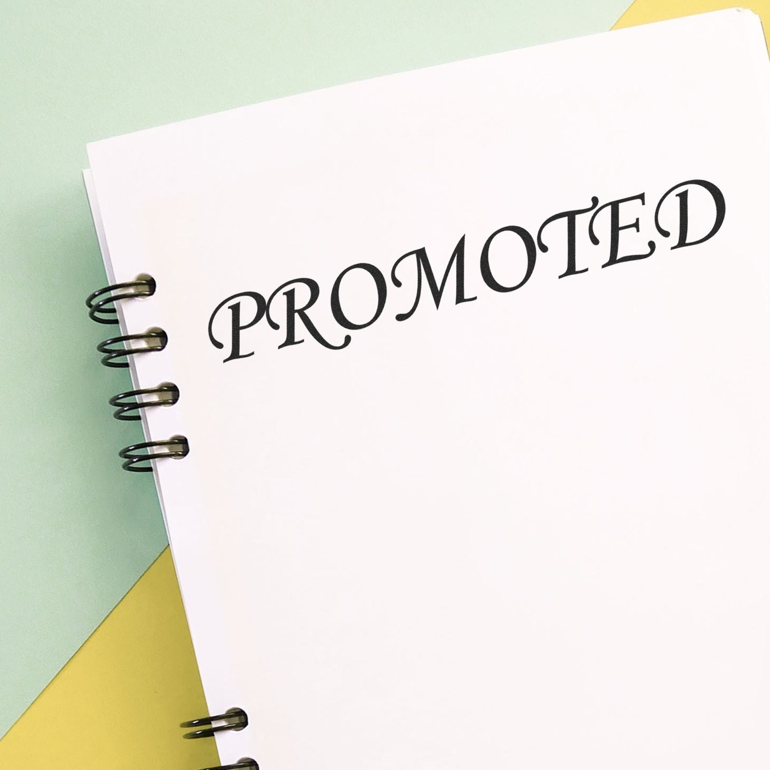 Notebook with a 'PROMOTED' rubber stamp mark on a pastel background, showcasing the promoted rubber stamp in use.