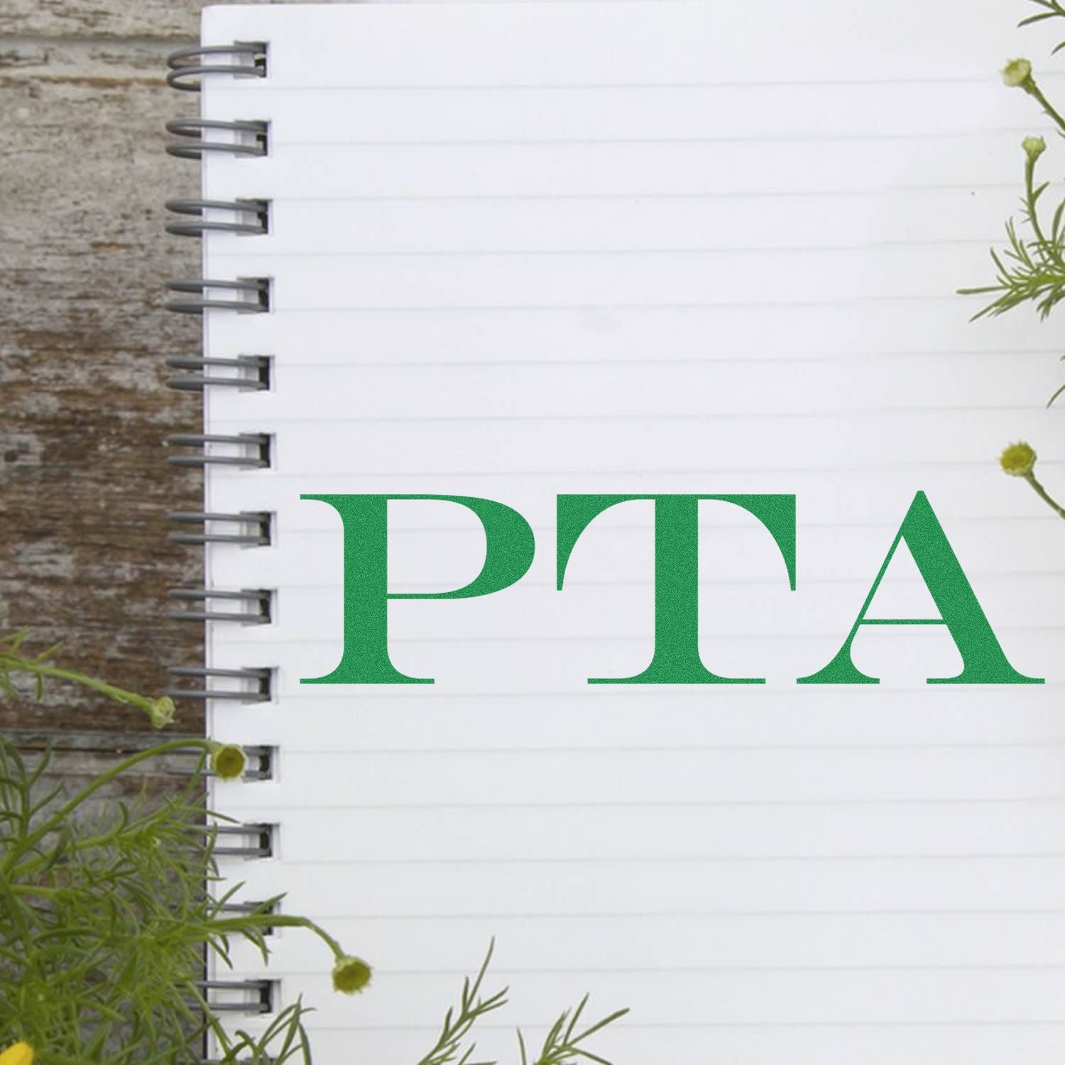 Self Inking PTA Stamp used on a white spiral notebook with green plants in the background.