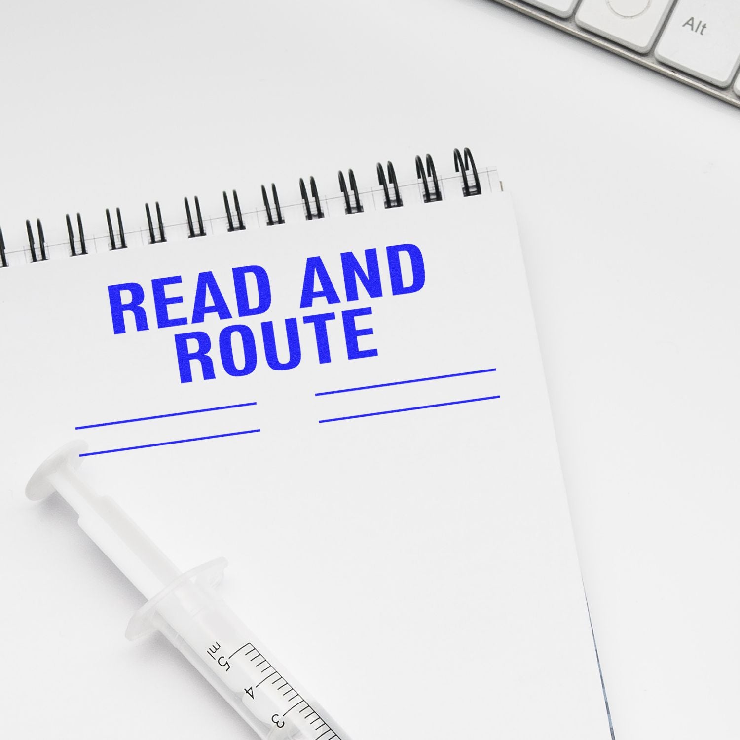 Large Self Inking Read and Route with Lines Stamp used on a white notepad, with a syringe and keyboard in the background.