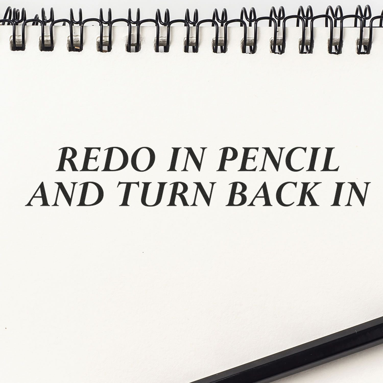 Redo In Pencil And Turn Back In Rubber Stamp impression on a spiral-bound notebook page with a pencil at the bottom.