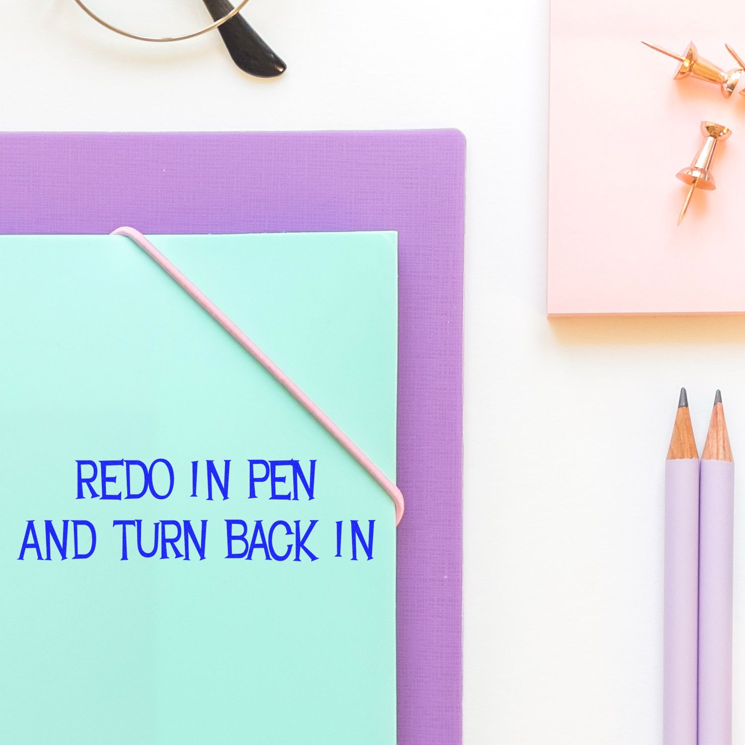 Self Inking Redo In Pen And Turn Back In Stamp on a desk with stationery items, including pencils, push pins, and folders.