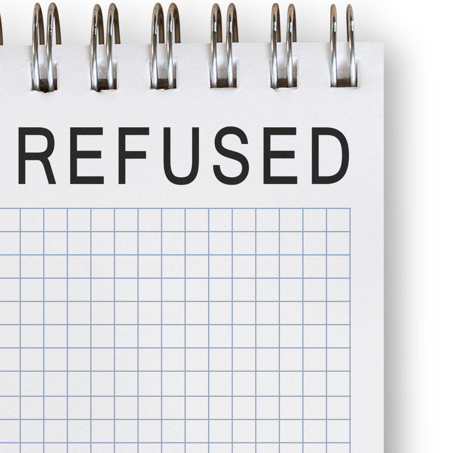 Large Refused Rubber Stamp marking REFUSED in bold black letters on a spiral-bound notebook with a grid pattern.