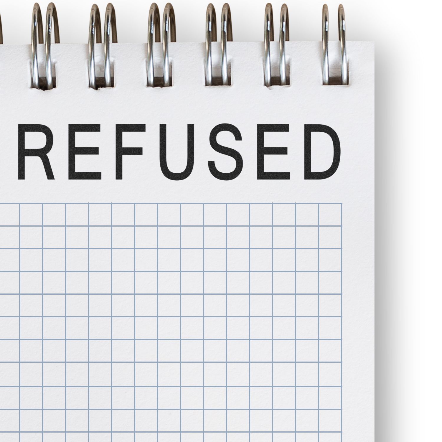 Self Inking Refused Stamp used on a spiral-bound notebook with a grid pattern, displaying the word REFUSED in bold black letters.