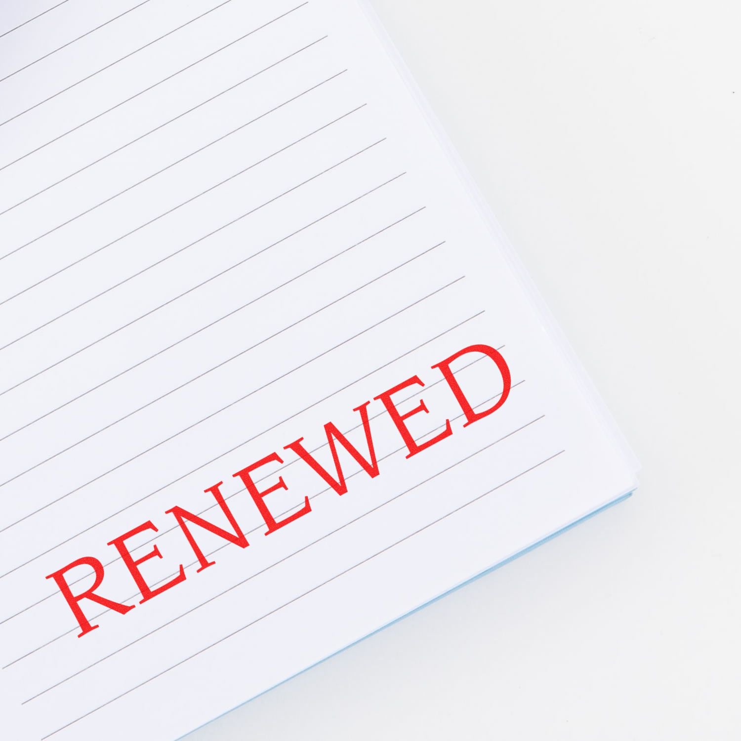 Large Renewed Rubber Stamp in red ink used on a lined notebook, displaying the word RENEWED prominently on the page.